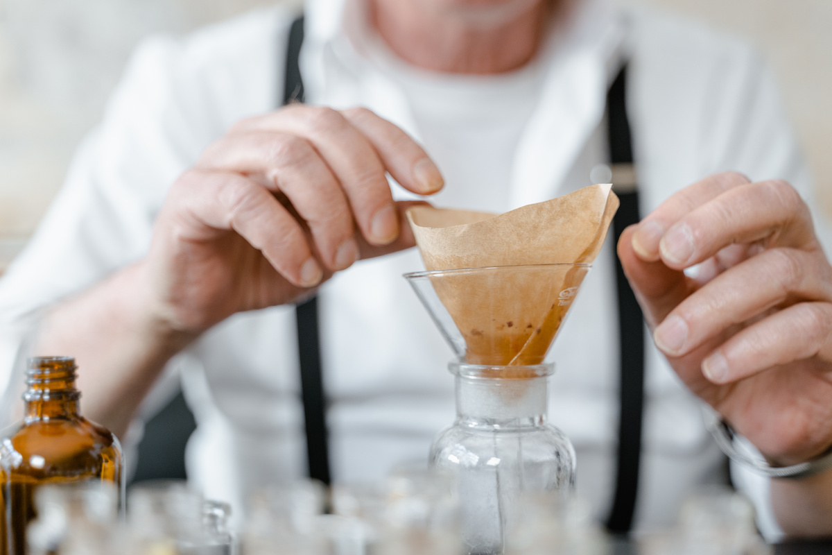 Hands of a Man Near a Glass Funnel with Paper Filter